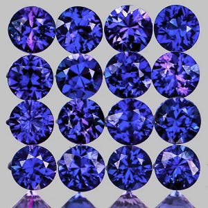 May include: Sixteen round, faceted gemstones in shades of deep blue and purple are arranged in a grid pattern. The gems have a brilliant cut, reflecting light and creating a sparkling effect. The background is a neutral gray.