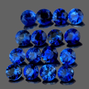 May include: A collection of 18 round, deep blue gemstones. The gemstones are arranged in three rows of six, with the top row slightly offset from the bottom two rows.