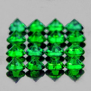 May include: A collection of 18 green faceted gemstones arranged in a grid pattern. The gemstones are cut in a triangular shape and have a shiny, reflective surface.