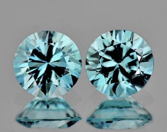 Puede incluir: Dos piedras preciosas redondas, facetadas, azules con un patrón en forma de estrella en el centro.