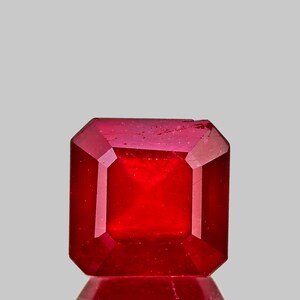 以下が含まれることがあります： 正方形でファセットカットされた深紅の宝石。宝石は白い背景に置かれています。
