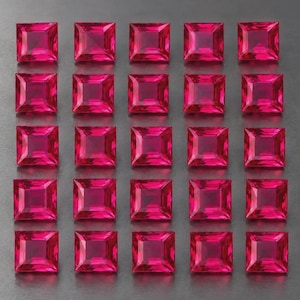 May include: A collection of twenty-five square-cut, vibrant pinkish-red gemstones arranged in a five-by-five grid. Each gemstone features a faceted surface that reflects light, creating a uniform appearance across all pieces in the display.