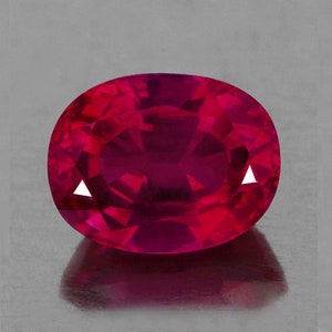 May include: A deep red oval-shaped gemstone with a faceted cut.