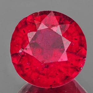 Può includere: Una pietra preziosa di rubino rosso intenso con taglio a faccette. La pietra preziosa è rotonda e ha un'alta lucidatura.