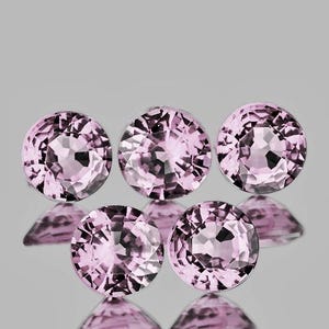 Può includere: Cinque pietre preziose rotonde e sfaccettate di colore rosa chiaro disposte in un gruppo. Ogni pietra presenta un taglio brillante con molteplici sfaccettature triangolari e trapezoidali che riflettono la luce, creando un aspetto scintillante.