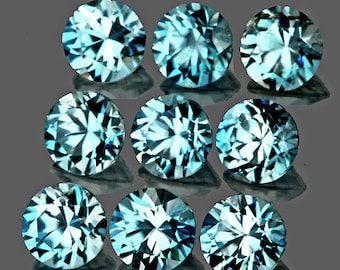 Puede incluir: Nueve gemas redondas y facetadas de color azul claro dispuestas sobre una superficie gris oscuro. Las gemas tienen un corte brillante, que refleja la luz creando un efecto brillante. Adecuado para la fabricación de joyas.
