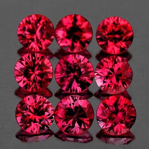 Puede incluir: Nueve piedras preciosas redondas y facetadas de color rojo. Las piedras preciosas están dispuestas en tres filas de tres.