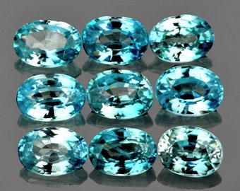 May include: Nine oval-shaped blue gemstones with a light blue hue. The gemstones are arranged in three rows of three.