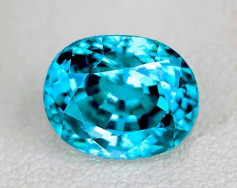 Könnte beinhalten: Ein leuchtend blauer ovaler Edelstein mit facettiertem Schliff. Der Edelstein hat eine leuchtende, klare Farbe und eine glatte, polierte Oberfläche.