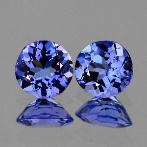 May include: Two round, faceted, blue gemstones. The gemstones are cut in a round shape and have a brilliant, faceted surface.