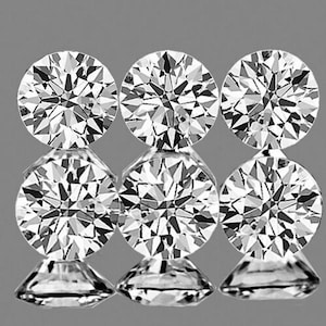 May include: Six round, clear, faceted gemstones arranged in two rows of three. The gemstones are set against a gray background.