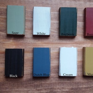 May include: A collection of 10 paint color samples, each with a name label. The colors include pewter, sage, white, bayberry, barn red, colonial blue, black, dutch blue, cream, and mustard.