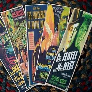 May include: Five vintage movie poster bookmarks featuring classic horror films. The bookmarks are printed on cardstock and feature black and white images of the films' stars. The titles of the films are printed in bold, white letters. The bookmarks are in excellent condition.