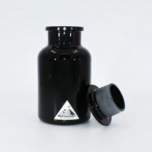 May include: A black glass jar with a black lid and a white label that says "MyPharmJar" with a pyramid and an eye graphic. Everything good is in a jar.