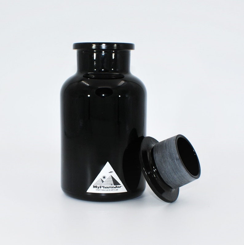 May include: A black glass jar with a black lid and a white label that says "MyPharmJar" with a pyramid and an eye graphic. Everything good is in a jar.