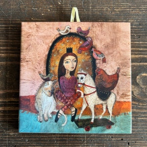 Può includere: Un'illustrazione fantasiosa di una ragazza con una corona, che indossa un vestito viola e cavalca un cavallo a dondolo bianco. La ragazza è circondata da uccelli colorati e un gatto. Lo sfondo è una superficie testurizzata rosa e marrone.