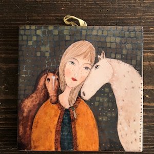 May include: A painting of a woman with blonde hair and freckles, wearing a brown and orange jacket, with two horses on either side of her. The background is a mosaic of brown and green squares.