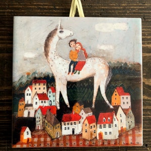 Puede incluir: Un unicornio blanco con una silla de montar roja y blanca, llevando a un niño y una niña, se encuentra sobre un pueblo de casas coloridas con techos rojos. El cielo está gris con nubes de lluvia y algunas gotas de lluvia caen.