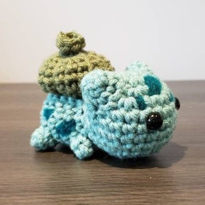 May include: A crocheted green and blue Squirtle Pokemon plush toy with a green shell on its back.