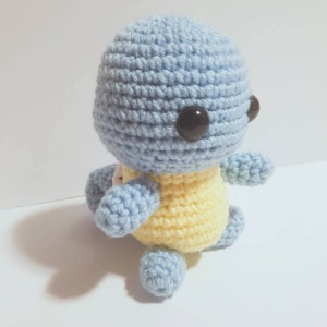 May include: A crocheted blue and yellow Squirtle plush toy with black eyes.
