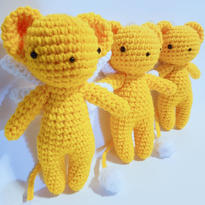 May include: Three yellow crocheted plush toys with white wings and tails. The toys have black eyes and are in a row.