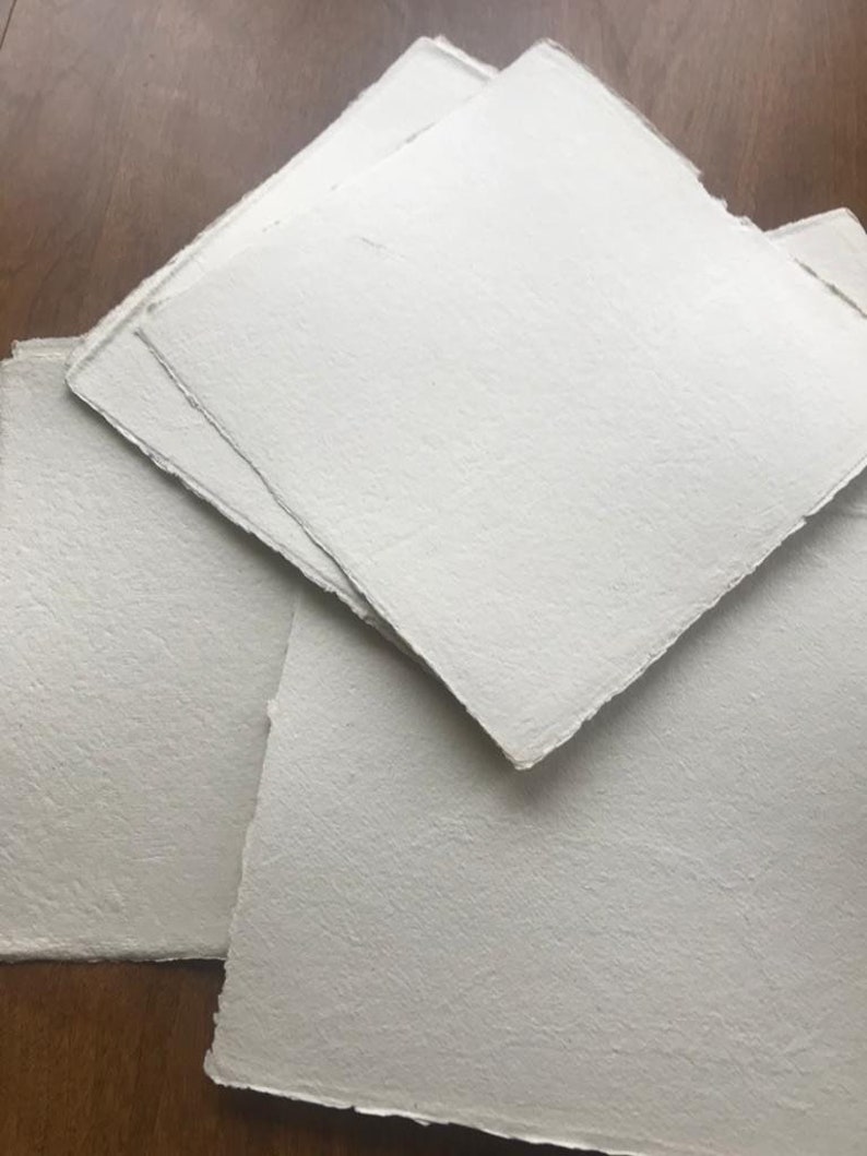 Puede incluir: Una pila de hojas de papel blanco texturizado con bordes irregulares.