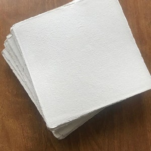 Puede incluir: Una pila de hojas de papel blanco hechas a mano con una superficie texturizada.