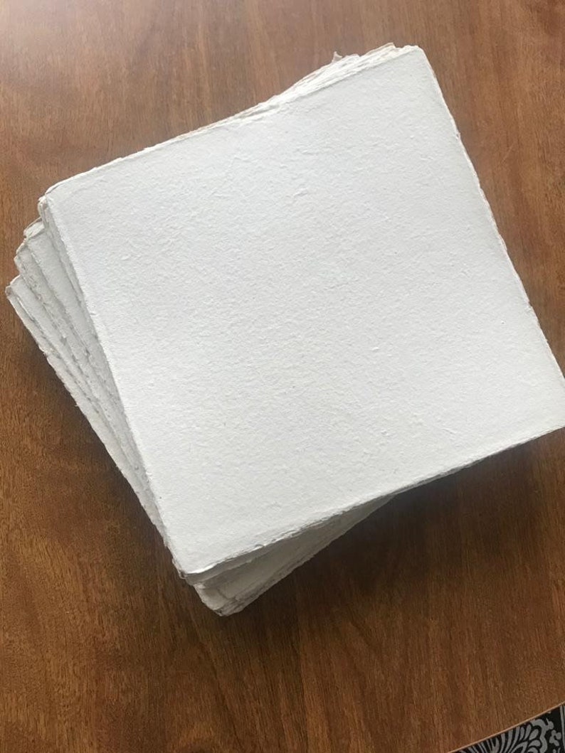 Puede incluir: Una pila de hojas de papel blanco hechas a mano con una superficie texturizada.