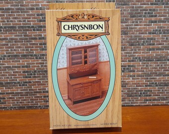 May include: A box for a model kit of a wooden hutch with glass doors. The box is brown with a green oval around a picture of the finished model. The text on the box reads "CHRYSNBON" and "MODEL KIT F 285".