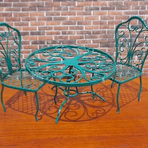 May include: A green metal patio set with a round table and two chairs. The table and chairs have a decorative, swirling design.