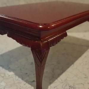May include: A mahogany wood coffee table with a rectangular top and four carved legs. The table has a dark, polished finish.
