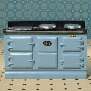 May include: A miniature light blue stove with a black top and silver burners. The stove has four doors and a central panel with the letters "CHE". A small, detailed replica of a kitchen appliance.