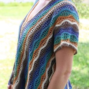 Pu&ograve; includere: Un top all'uncinetto con un motivo a righe ondulate in tonalit&agrave; di blu, verde, marrone e arancio. Il top ha una scollatura a V e maniche corte.