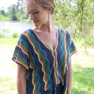 Pu&ograve; includere: Un top all'uncinetto con un motivo a righe in tonalit&agrave; di blu, verde, marrone e bianco. Il top ha una scollatura a V e maniche corte.