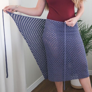 May include: A purple crochet wrap skirt with a tie closure. The skirt is made of a lightweight, open-weave fabric and is perfect for warm weather.