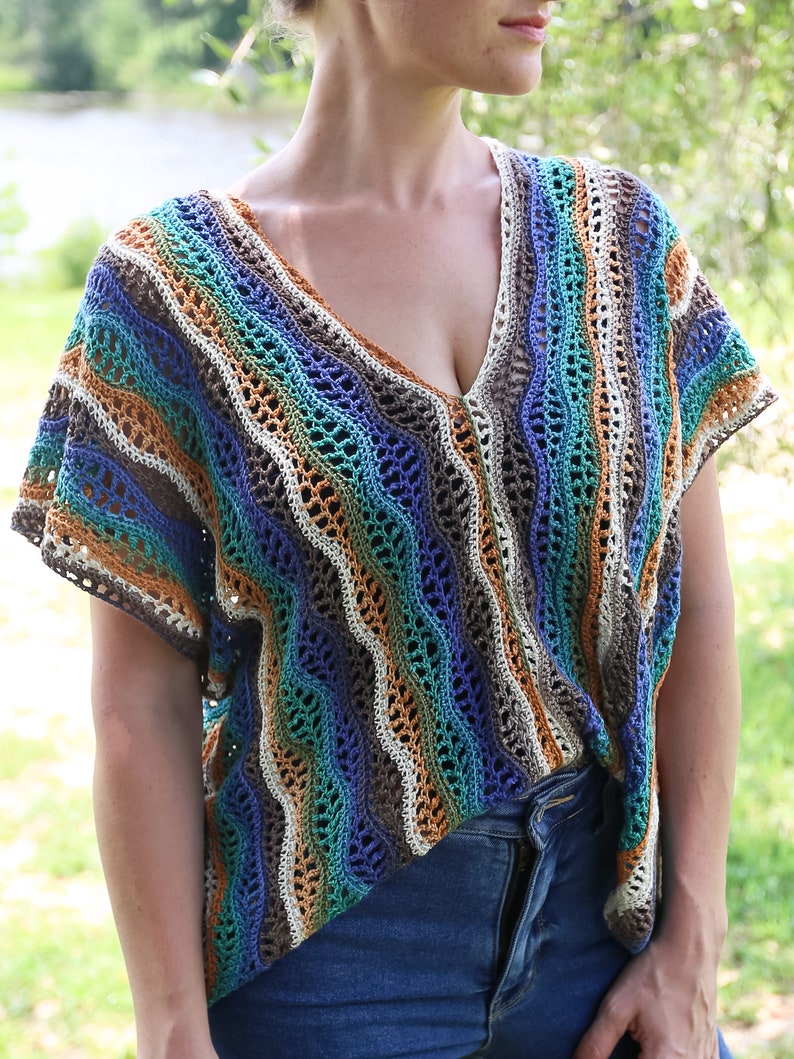 Pu&ograve; includere: Un top all'uncinetto con un motivo a righe in tonalit&agrave; di blu, verde, marrone e bianco. Il top ha una scollatura a V e maniche corte.