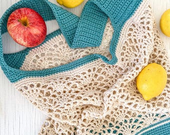 May include: A crocheted market bag with teal and beige stripes. The bag is made of a mesh material and is lying on a white surface with apples and lemons around it.