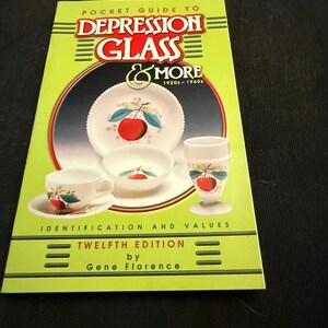 May include: A green book titled "Pocket Guide to Depression Glass & More 1920s-1960s" with a white background and images of depression glass. The book is the twelfth edition by Gene Florence.