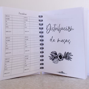 May include: Open notebook with spiral binding, featuring pages with printed forms and handwritten text. The right page displays the words "Distribuci&oacute;n de mesas" with a floral illustration. The left page has the word "Proveedores" and contact fields.