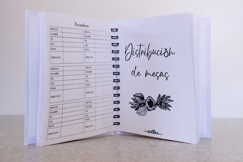 May include: Open notebook with spiral binding, featuring pages with printed forms and handwritten text. The right page displays the words "Distribuci&oacute;n de mesas" with a floral illustration. The left page has the word "Proveedores" and contact fields.
