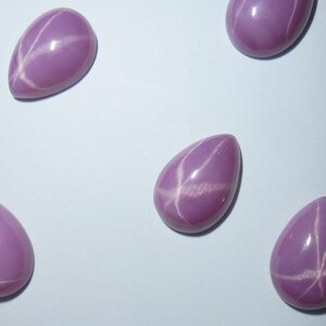 May include: Five pink star sapphires with a pear shape and white star patterns.