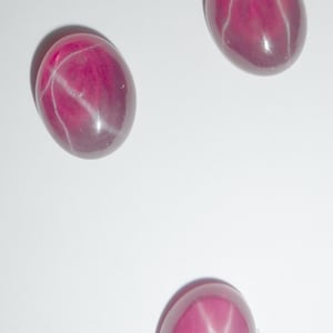 Op de afbeelding: Drie roze ster-saffieren met een witte ster in het midden van elke steen.