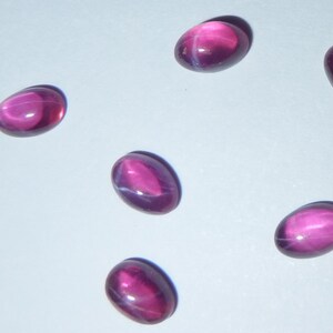 May include: Six oval-shaped, pink star sapphires with a white star in the center.