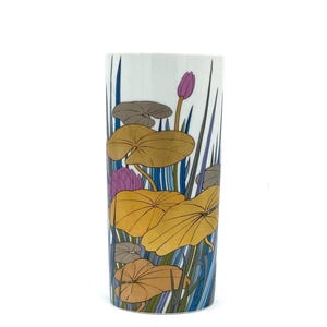 Könnte beinhalten: Eine weiße Keramikvase mit einem Blumendesign. Die Vase zeigt ein Muster aus gelben, orangefarbenen, blauen und violetten Seerosen und Blättern auf weißem Hintergrund.