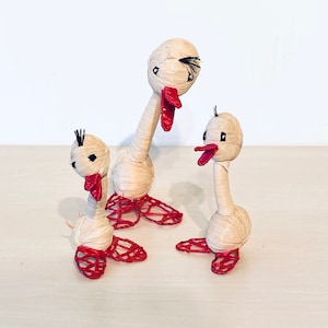 Three small decorative ducks made of raffia with red beak and red feet, duck for decoration