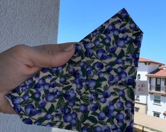 May include: A white bandana with a blueberry print. The bandana is folded in a triangle shape and is being held by a hand. The bandana has a small white tag with the text "Sew Much Love" on it.