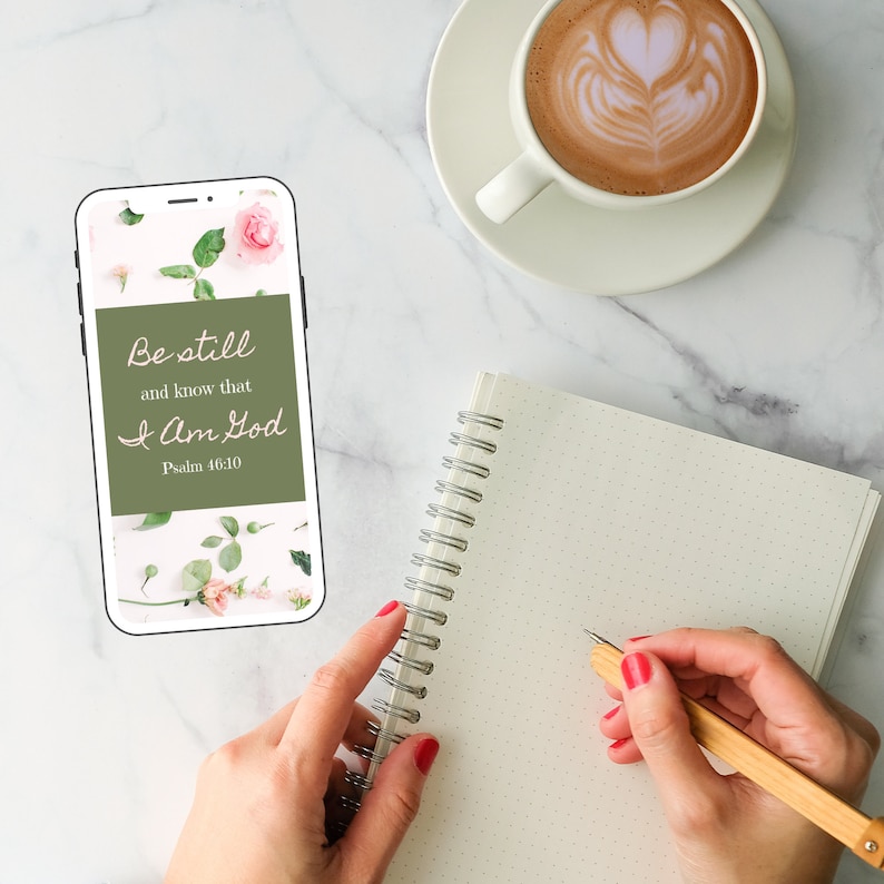 K&ouml;nnte beinhalten: Ein wei&szlig;es Smartphone mit gr&uuml;nem Hintergrund, auf dem der Text "Be still and know that I am God, Psalm 46:10" zu sehen ist. Das Telefon liegt auf einer wei&szlig;en Marmorfl&auml;che mit einer Tasse Kaffee und einem Notizbuch.