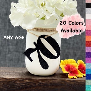 May include: White mason jar with a black glitter number 70 on it. The jar is decorated with twine and has white flowers in it. The text "ANY AGE" is visible in the image. The text "20 Colors Available" is also visible in the image.