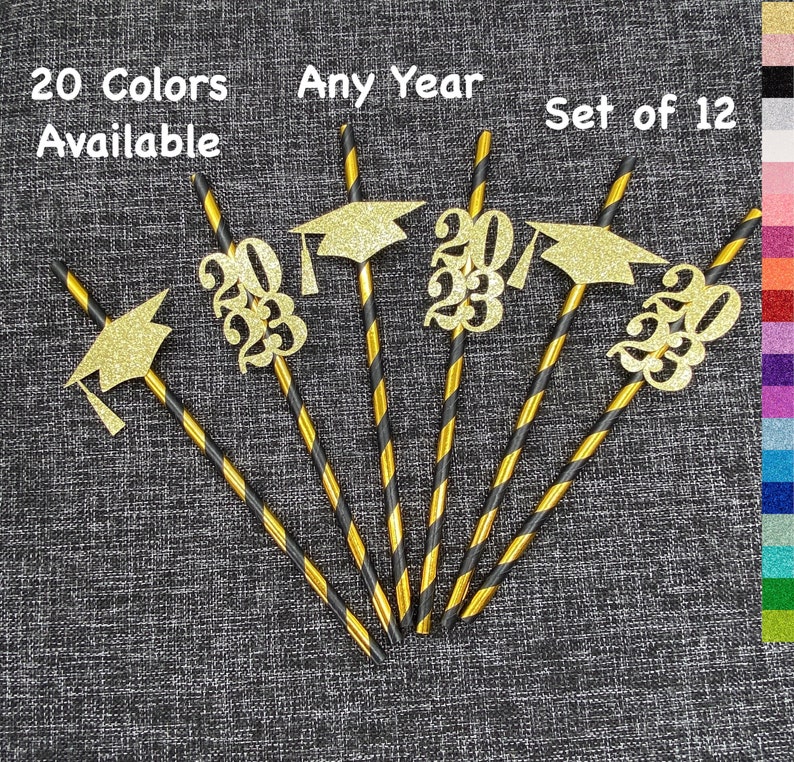 May include: Set of 12 graduation straws with gold glitter graduation caps and the year 2023. The straws are black and gold striped.