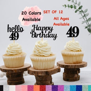 May include: Three cupcakes with black and white frosting toppers that say "hello 49", "happy birthday", and "49". The cupcakes are on wooden cake stands. The text "20 Colors Available" and "Set of 12 All Ages Available" is in the background.